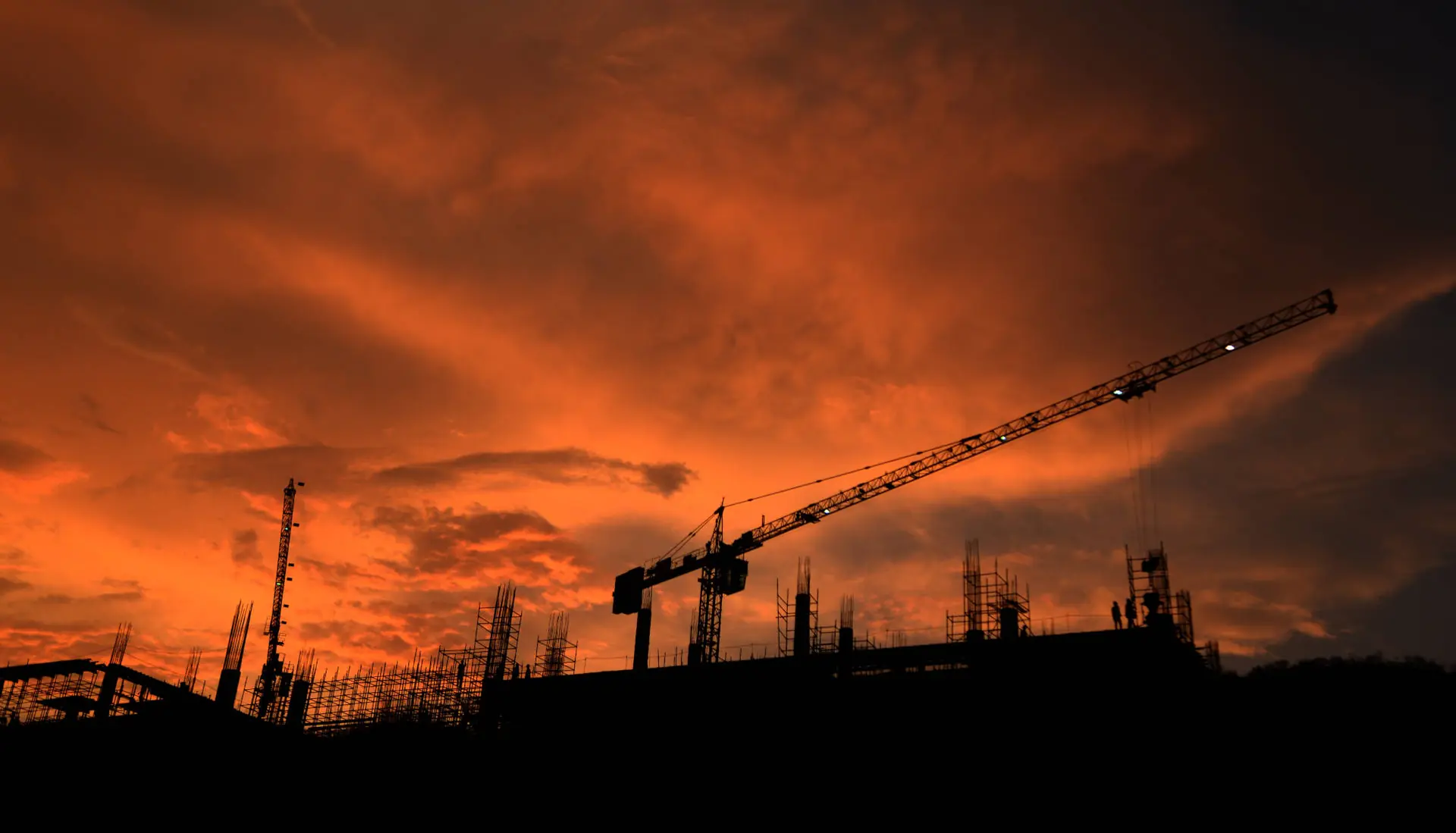 Tower crane over a construction site at sunset